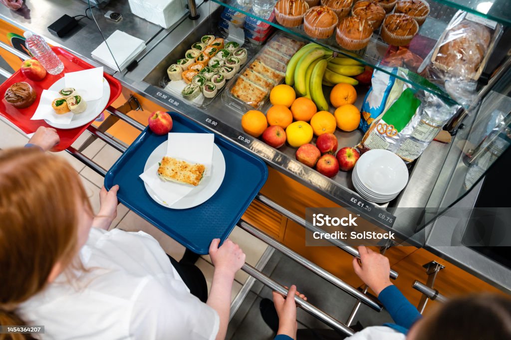 A high angle view of a young teenage girl who is looking at the options for her lunch in the school she goes to in the North East of England. There is plenty of choice of fresh fruit and snacks to choose from in the chiller cabinet.
